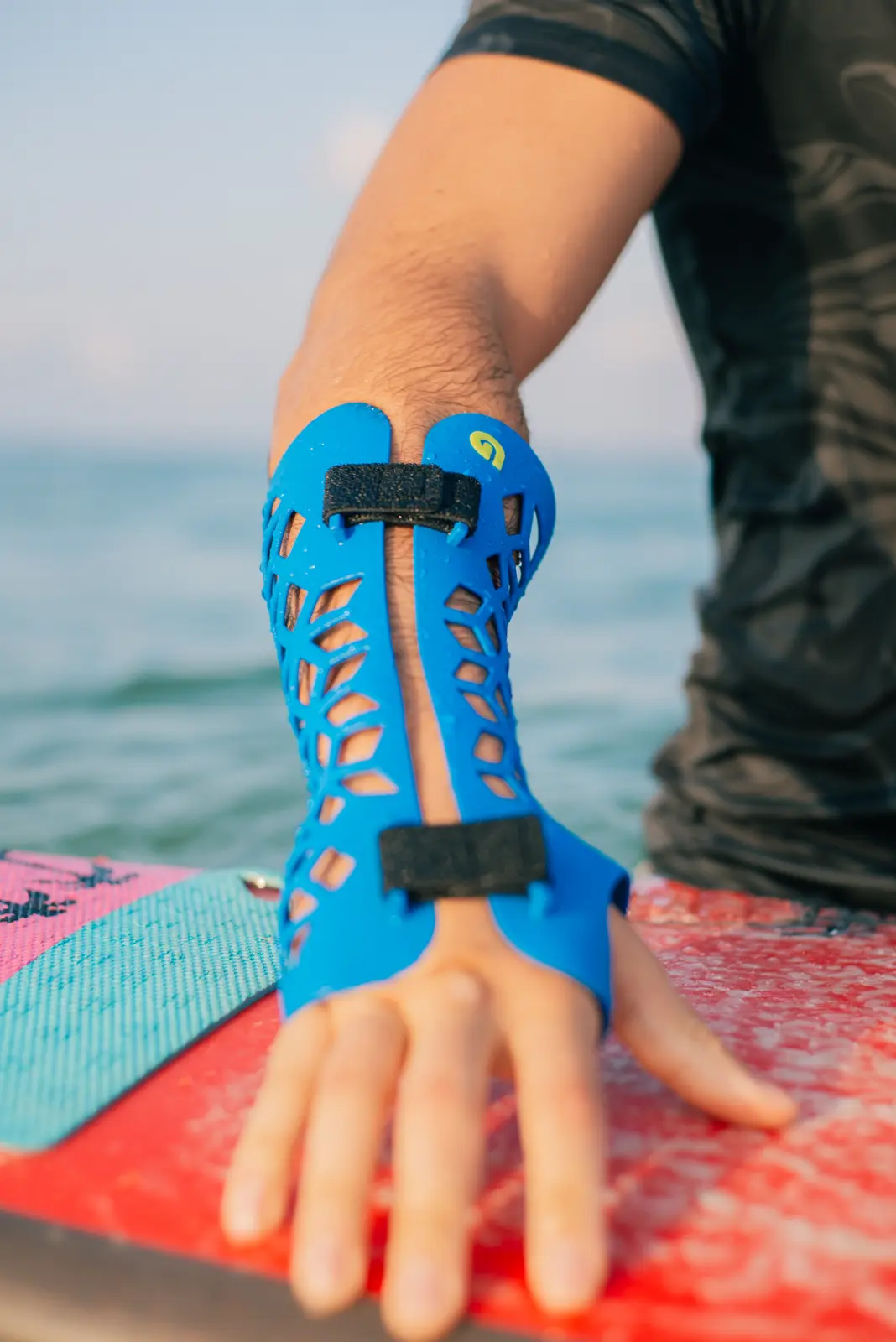A blue Gero3D cast on a forearm, resting on a surfboard